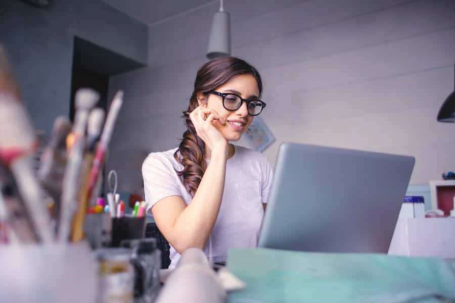 Frau sitzt in ihrem Arbeitszimmer an einem Laptop